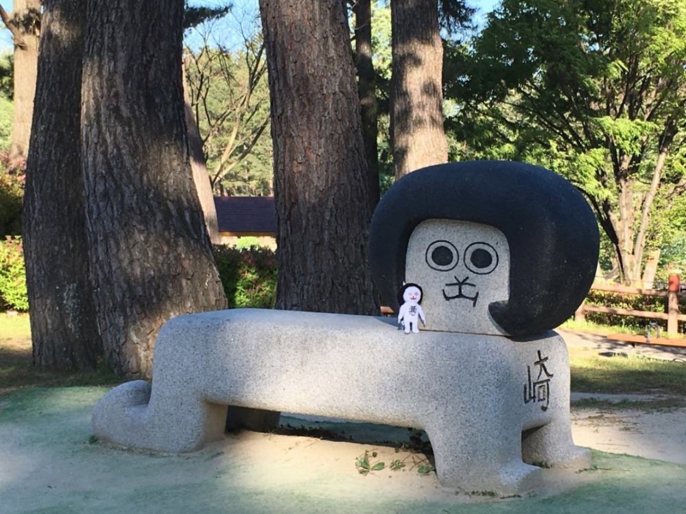 岡崎君的頭其實是以岡崎市的”岡”這個漢字所畫出的頭像，石椅的旁邊可以發現岡崎的”崎”。