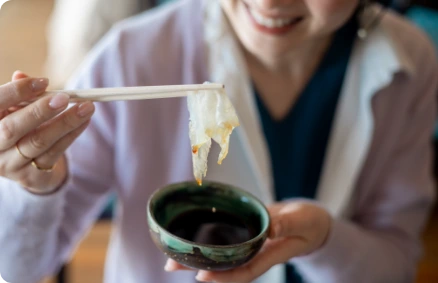 ふぐ料理を箸で味わう女性