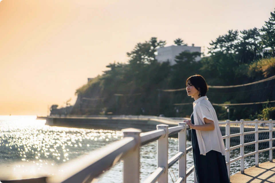 夕暮れの海辺でくつろぐ女性