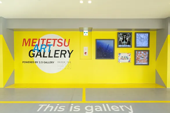 黄色とグレーを基調とした現代的な空間に、4点のデジタルアートのような作品が展示されている「MEITETSU ART GALLERY」の展示イメージ。作品は暗い色調のものが中心で、明るい壁とのコントラストが印象的。
